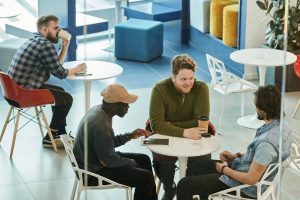 Three colleagues having a conversation at an office cafeteria